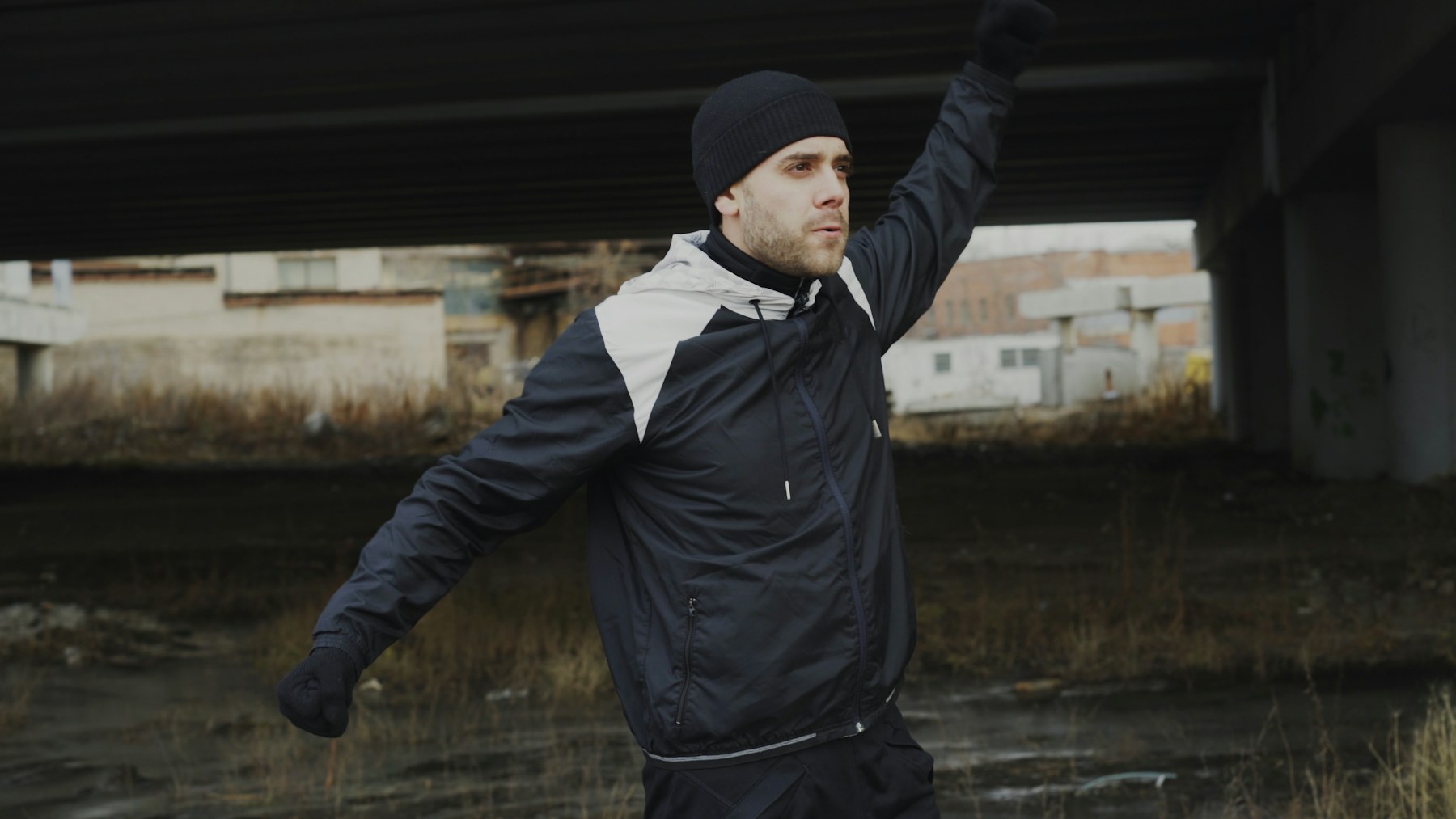 Person in Sportkleidung beim Aufwärmen unter einer Brücke
